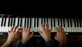 Playing four male hands on the piano. palms lie on the keys and play the keyboard instrument in a music school. student learns to