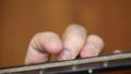 Playing the guitar brown close-up fingers busting the strings