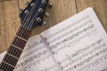 Playing guitar... Close-up photo of guitar neck and music notes against of wooden background.