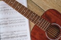 Playing Guitar. Close up view of brown acoustic guitar with music notes against wooden floor Royalty Free Stock Photo