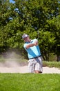 Playing his way out of a ditch. A mature man playing a golf shot from a sand bunker. Royalty Free Stock Photo