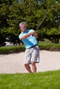 Playing his way out of a ditch. A mature man playing a golf shot from a sand bunker. Royalty Free Stock Photo