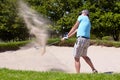 Playing his way out of a ditch. A mature man playing a golf shot from a sand bunker. Royalty Free Stock Photo