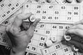 Playing lotto game, black and white. Person holding cube with figure on bingo card background. Nostalgia lifestyle. Retro games