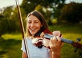 Playing with nature all around always makes her happy. a young girl playing a violin outdoors. Royalty Free Stock Photo