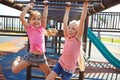 Playing outside makes them happier, healthier and smarter. two little girls hanging on the monkey bars at the playground