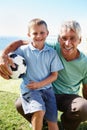 Playing soccer with grandpa. a young boy sitting on his grandfathers knee while holding a soccer ball. Royalty Free Stock Photo