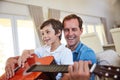 Playing some tunes with dad. a father and his young son sitting together in the living room at home playing guitar. Royalty Free Stock Photo