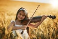 Playing to the tune of nature. Portrait of a cute little girl playing the violin while standing in a cornfield. Royalty Free Stock Photo