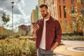 Playlist settings. Happy young man with stubble in headphones listening to the music and holding mobile phone while Royalty Free Stock Photo