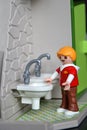 Playmobil figure, little boy washing hands under the water tap.