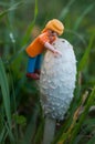 Playmobil figurine climbing on giant coprinus in a meadow in outdoor