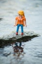 PLaymobil figurine on rock in middle of the river in outdoor