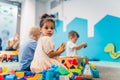 Playtime at nursery school. Toddlers sitting on the floor and playing with building blocks, colorful cars and other toys Royalty Free Stock Photo