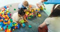 Playtime at nursery school. Toddlers with their teacher sitting on the floor and playing with building blocks, colorful Royalty Free Stock Photo