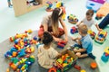 Playtime at nursery school. Toddlers with their teacher sitting on the floor and playing with building blocks, colorful Royalty Free Stock Photo
