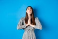 Pleading woman in dress begging for wish come true, supplicating god, standing against blue background Royalty Free Stock Photo