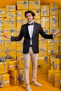 Pleasant Affable caucasian brunette guy in business suit stands on background full of gifts, smiling Royalty Free Stock Photo