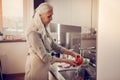 Pleasant aged woman washing a red tomato