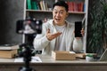 Pleasant asian man opening parcel box with new smartphone