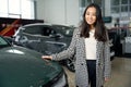 Pleasant asian woman stands near a new car
