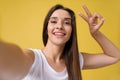 Pleasant attractive girl making selfie in studio and laughing. Good-looking young woman with brown hair taking picture