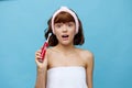 a pleasant, beautiful young woman stands on a blue background in a towel, holding a red toothbrush in her hand, looking Royalty Free Stock Photo