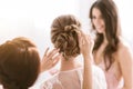 Pleasant bridesmaids helping the bride with her hairstyle