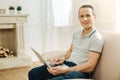 Pleasant cheerful man smiling while holding a modern laptop