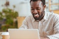 Pleasant cheerful man smiling while working on laptop Royalty Free Stock Photo