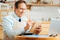 Pleasant clever man smiling and writing in his notebook. Royalty Free Stock Photo