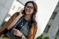 Pleasant conversation with friend. Young charming and stylish woman talking on smartphone and smiling while walking on Royalty Free Stock Photo