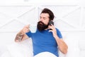 Pleasant conversation. Good morning. Hello dear. Bearded man using mobile technology in bed. Handsome guy talking on Royalty Free Stock Photo