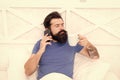 Pleasant conversation. Good morning. Hello dear. Bearded man using mobile technology in bed. Handsome guy talking on Royalty Free Stock Photo