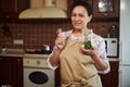 Pleasant multiethnic woman, housewife cute smiles looking at camera, holding a can for canning and fresh garlic