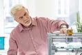 Pleasant elderly man using 3D printer in the office