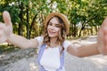 Pleasant fair-haired girl in straw hat making selfie. Outdoor shot of lovable white woman taking pi Royalty Free Stock Photo