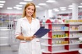 Pleasant female pharmacist writing on clipboard at pharmacy, make notes Royalty Free Stock Photo