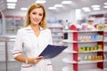 Pleasant female pharmacist writing on clipboard at pharmacy, make notes Royalty Free Stock Photo