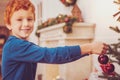 Pleasant ginger-haired boy decorating Christmas tree
