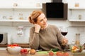 Pleasant ginger mature woman wearing sweater while staying in kitchen alone