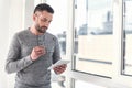 Pleasant guy with stubble is analyzing information using gadget Royalty Free Stock Photo