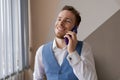 Pleasant handsome bearded man in shirt and waistcoat talking on phone, ordering Royalty Free Stock Photo