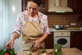 Pleasant housewife, beautiful multiethnic woman cooking pickled cucumbers in the home kitchen interior