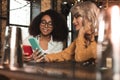 Pretty young women showing each other photos at bar