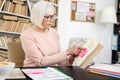 Pleasant mature woman marking book with sticker