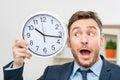 Pleasant office worker holding clock