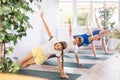 Pleasant preteen girl practicing side plank pose of yoga with her family