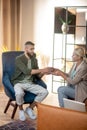 Pleasant psychoanalyst giving cup of tea to her patient