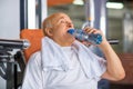 Pleasant senior man drinking water in gym